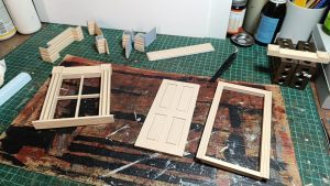 Proceso de construcción del diorama "Las Gemelas": recreación artesanal del pasillo del hotel Overlook con papel pintado geométrico en miniatura, carpintería detallada de puertas de hotel