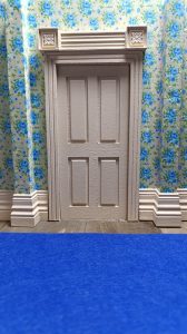 Proceso de construcción del diorama "Las Gemelas": recreación artesanal del pasillo del hotel Overlook con papel pintado geométrico en miniatura, carpintería detallada de puertas de hotel