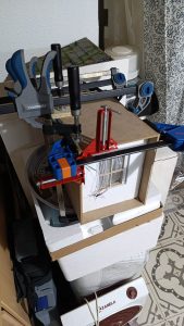 Proceso de construcción del diorama "Las Gemelas": recreación artesanal del pasillo del hotel Overlook con papel pintado geométrico en miniatura, carpintería detallada de puertas de hotel