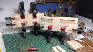 Proceso de construcción del diorama "Las Gemelas": recreación artesanal del pasillo del hotel Overlook con papel pintado geométrico en miniatura, carpintería detallada de puertas de hotel