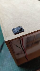 Proceso de construcción del diorama "Las Gemelas": recreación artesanal del pasillo del hotel Overlook con papel pintado geométrico en miniatura, carpintería detallada de puertas de hotel