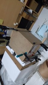 Proceso de construcción del diorama "Las Gemelas": recreación artesanal del pasillo del hotel Overlook con papel pintado geométrico en miniatura, carpintería detallada de puertas de hotel