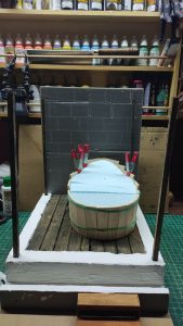 Proceso artesanal del diorama "El Nombre de la Rosa": recreación detallada de los baños del monasterio medieval con Berengario muerto en la bañera, modelado de texturas de piedra húmeda y envejecimiento de mobiliario de madera real