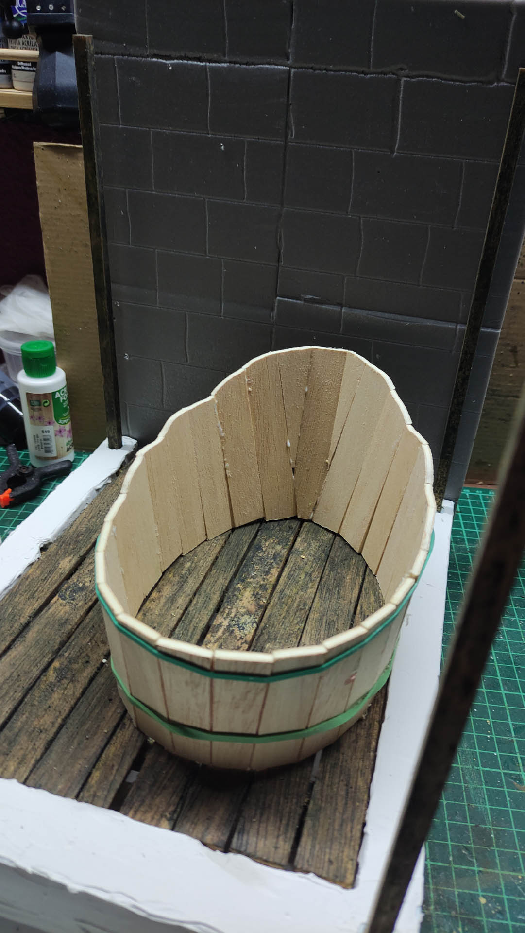 Proceso artesanal del diorama "El Nombre de la Rosa": recreación detallada de los baños del monasterio medieval con Berengario muerto en la bañera, modelado de texturas de piedra húmeda y envejecimiento de mobiliario de madera real