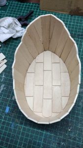 Proceso artesanal del diorama "El Nombre de la Rosa": recreación detallada de los baños del monasterio medieval con Berengario muerto en la bañera, modelado de texturas de piedra húmeda y envejecimiento de mobiliario de madera real