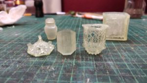 Proceso artesanal del diorama "El Nombre de la Rosa": recreación detallada de los baños del monasterio medieval con Berengario muerto en la bañera, modelado de texturas de piedra húmeda y envejecimiento de mobiliario de madera real