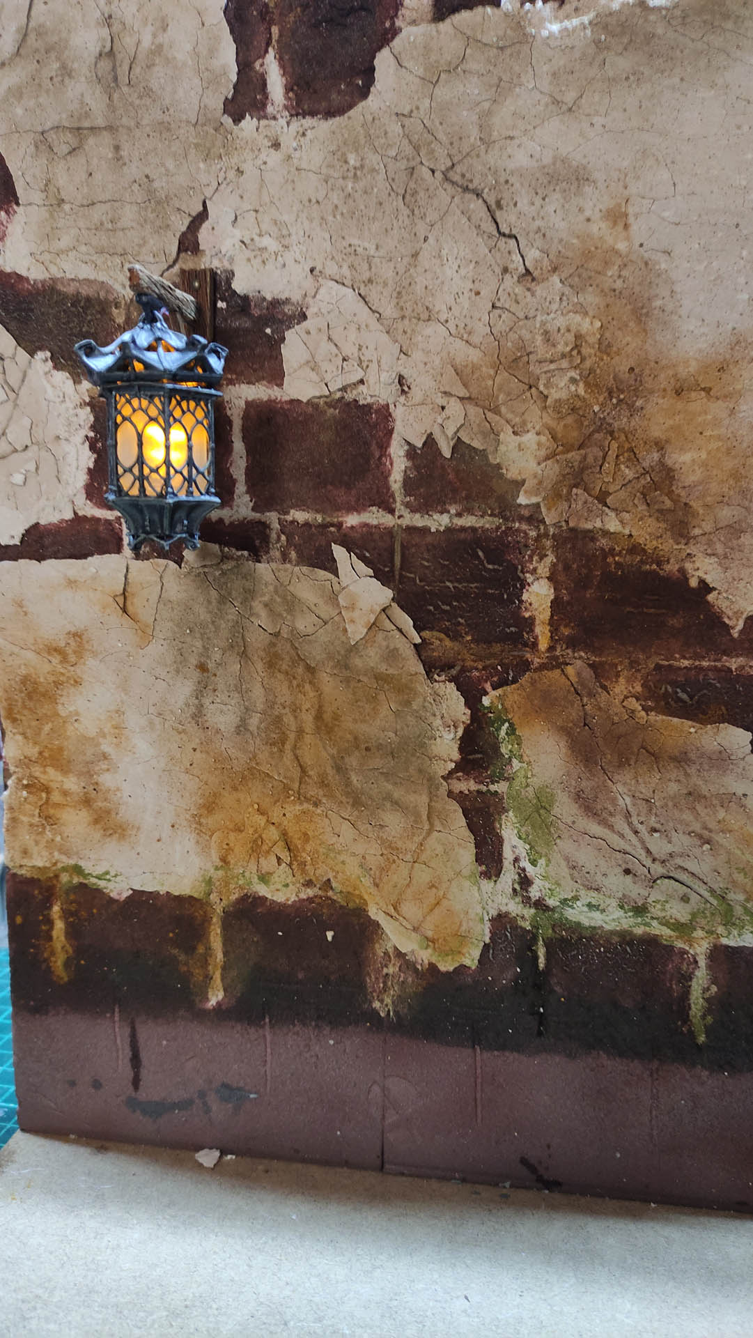 Proceso artesanal del diorama "El Nombre de la Rosa": recreación detallada de los baños del monasterio medieval con Berengario muerto en la bañera, modelado de texturas de piedra húmeda y envejecimiento de mobiliario de madera real