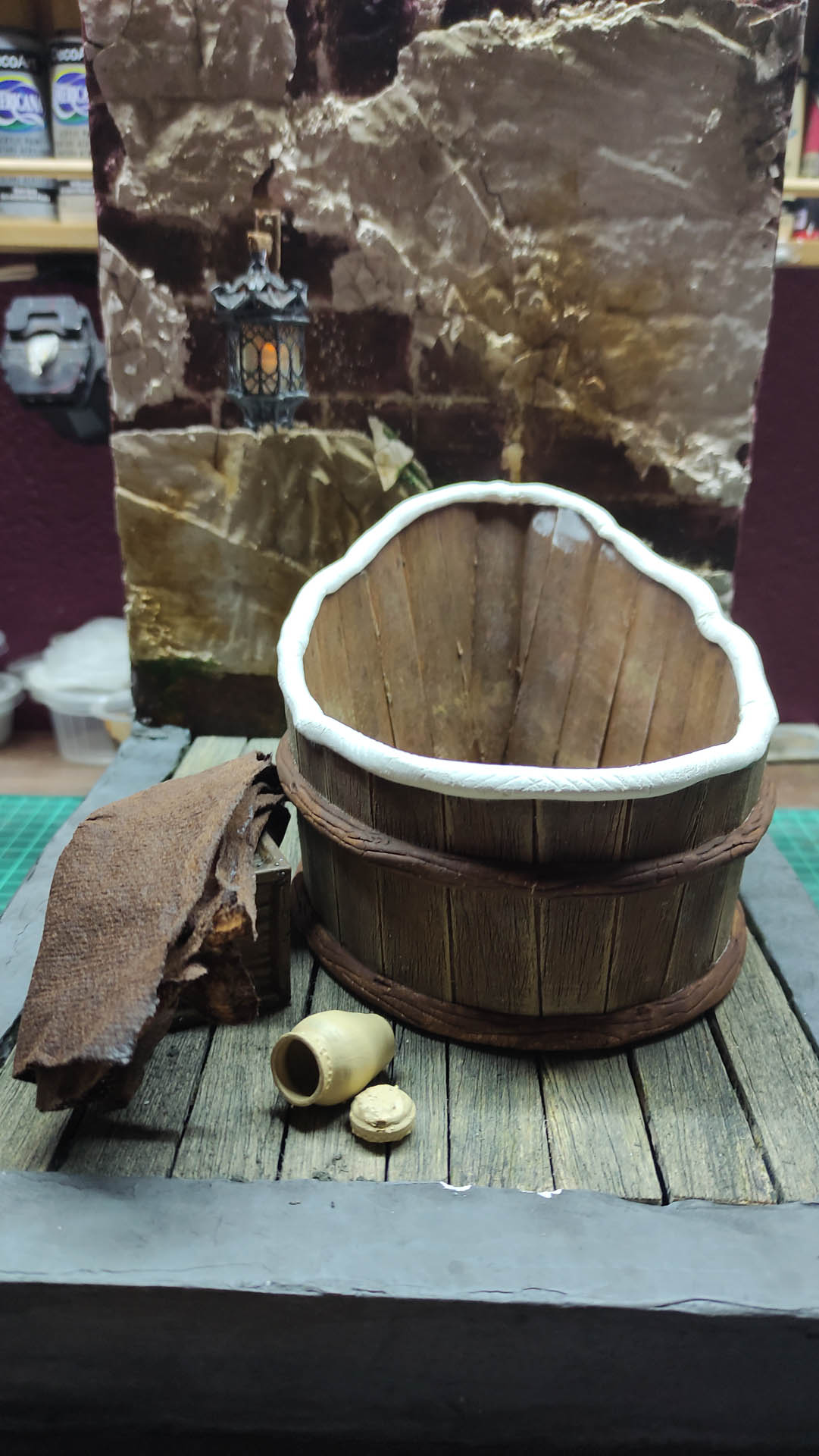 Proceso artesanal del diorama "El Nombre de la Rosa": recreación detallada de los baños del monasterio medieval con Berengario muerto en la bañera, modelado de texturas de piedra húmeda y envejecimiento de mobiliario de madera real