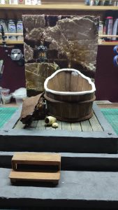 Proceso artesanal del diorama "El Nombre de la Rosa": recreación detallada de los baños del monasterio medieval con Berengario muerto en la bañera, modelado de texturas de piedra húmeda y envejecimiento de mobiliario de madera real