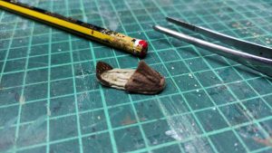 Proceso artesanal del diorama "El Nombre de la Rosa": recreación detallada de los baños del monasterio medieval con Berengario muerto en la bañera, modelado de texturas de piedra húmeda y envejecimiento de mobiliario de madera real