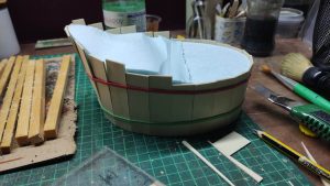 Proceso artesanal del diorama "El Nombre de la Rosa": recreación detallada de los baños del monasterio medieval con Berengario muerto en la bañera, modelado de texturas de piedra húmeda y envejecimiento de mobiliario de madera real