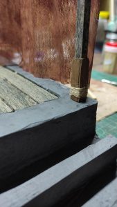 Proceso artesanal del diorama "El Nombre de la Rosa": recreación detallada de los baños del monasterio medieval con Berengario muerto en la bañera, modelado de texturas de piedra húmeda y envejecimiento de mobiliario de madera real