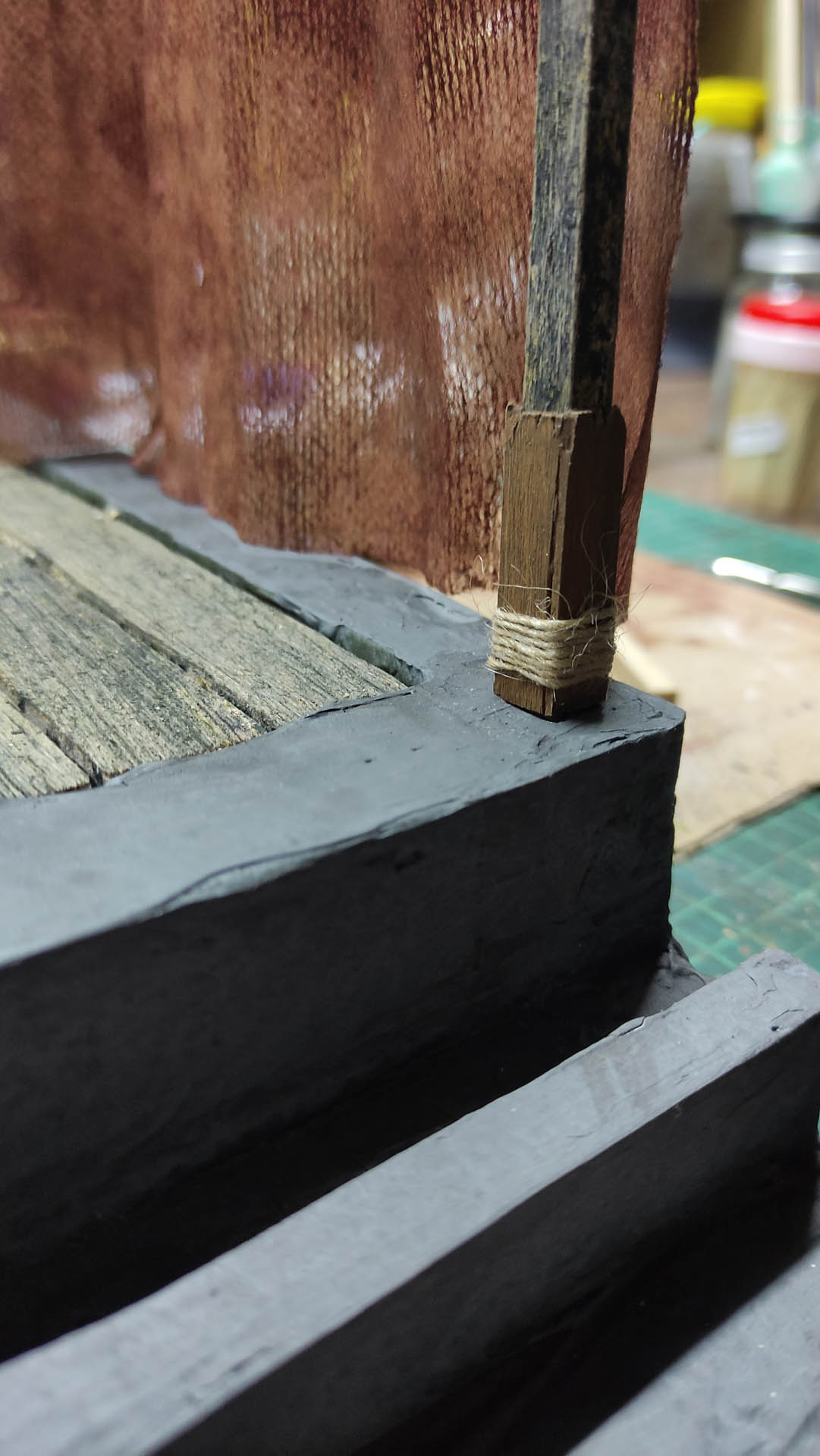 Proceso artesanal del diorama "El Nombre de la Rosa": recreación detallada de los baños del monasterio medieval con Berengario muerto en la bañera, modelado de texturas de piedra húmeda y envejecimiento de mobiliario de madera real