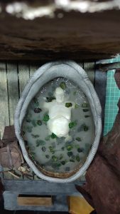 Proceso artesanal del diorama "El Nombre de la Rosa": recreación detallada de los baños del monasterio medieval con Berengario muerto en la bañera, modelado de texturas de piedra húmeda y envejecimiento de mobiliario de madera real