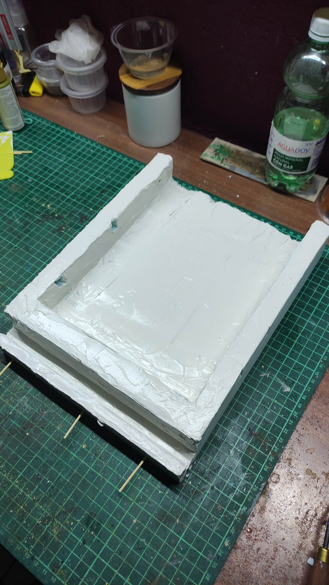 Proceso artesanal del diorama "El Nombre de la Rosa": recreación detallada de los baños del monasterio medieval con Berengario muerto en la bañera, modelado de texturas de piedra húmeda y envejecimiento de mobiliario de madera real