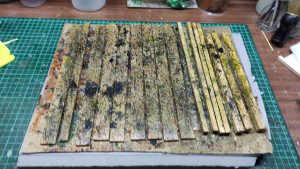 Proceso artesanal del diorama "El Nombre de la Rosa": recreación detallada de los baños del monasterio medieval con Berengario muerto en la bañera, modelado de texturas de piedra húmeda y envejecimiento de mobiliario de madera real