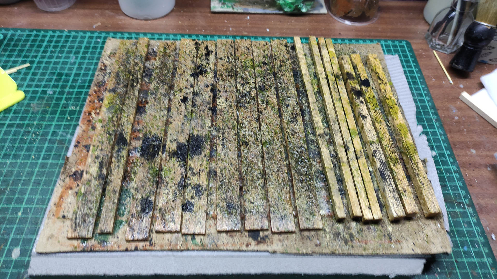 Proceso artesanal del diorama "El Nombre de la Rosa": recreación detallada de los baños del monasterio medieval con Berengario muerto en la bañera, modelado de texturas de piedra húmeda y envejecimiento de mobiliario de madera real