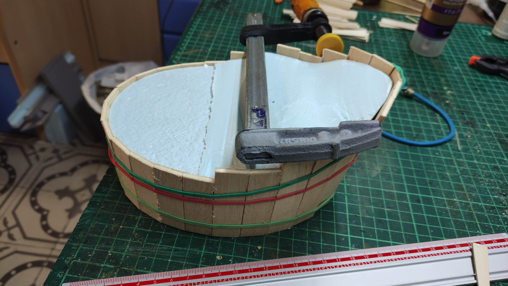 Proceso artesanal del diorama "El Nombre de la Rosa": recreación detallada de los baños del monasterio medieval con Berengario muerto en la bañera, modelado de texturas de piedra húmeda y envejecimiento de mobiliario de madera real