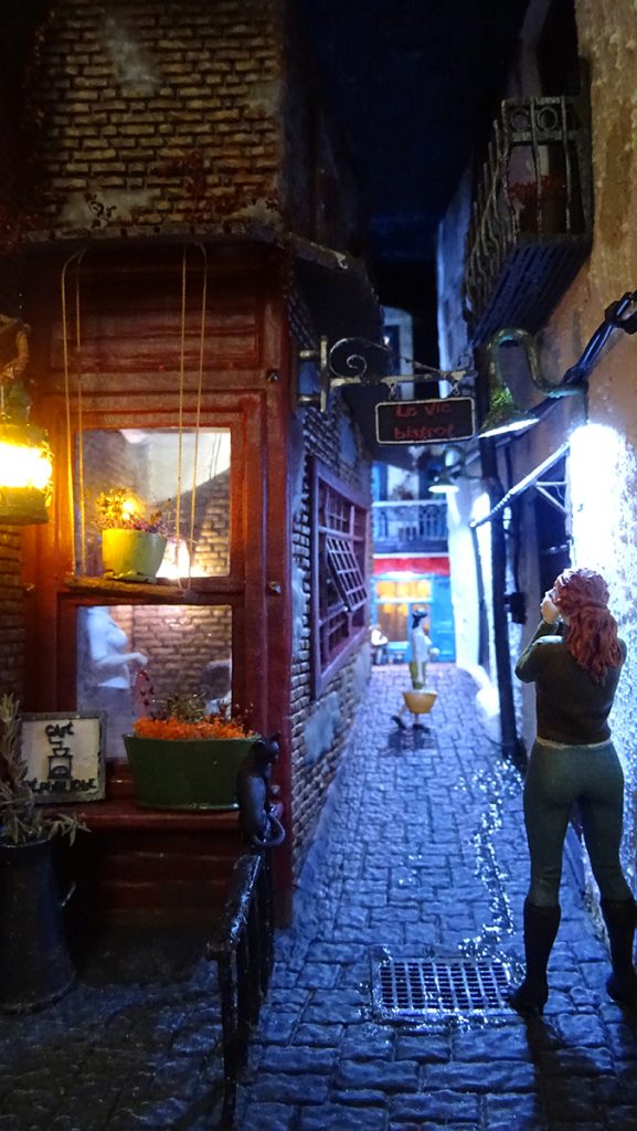 Diorama artesanal de calle típica de París con iluminación LED realista. Sujetalibros miniatura (Booknook) de estilo europeo con fachadas de ladrillo y detalles cinematográficos, hecho a mano por 27dioramas.