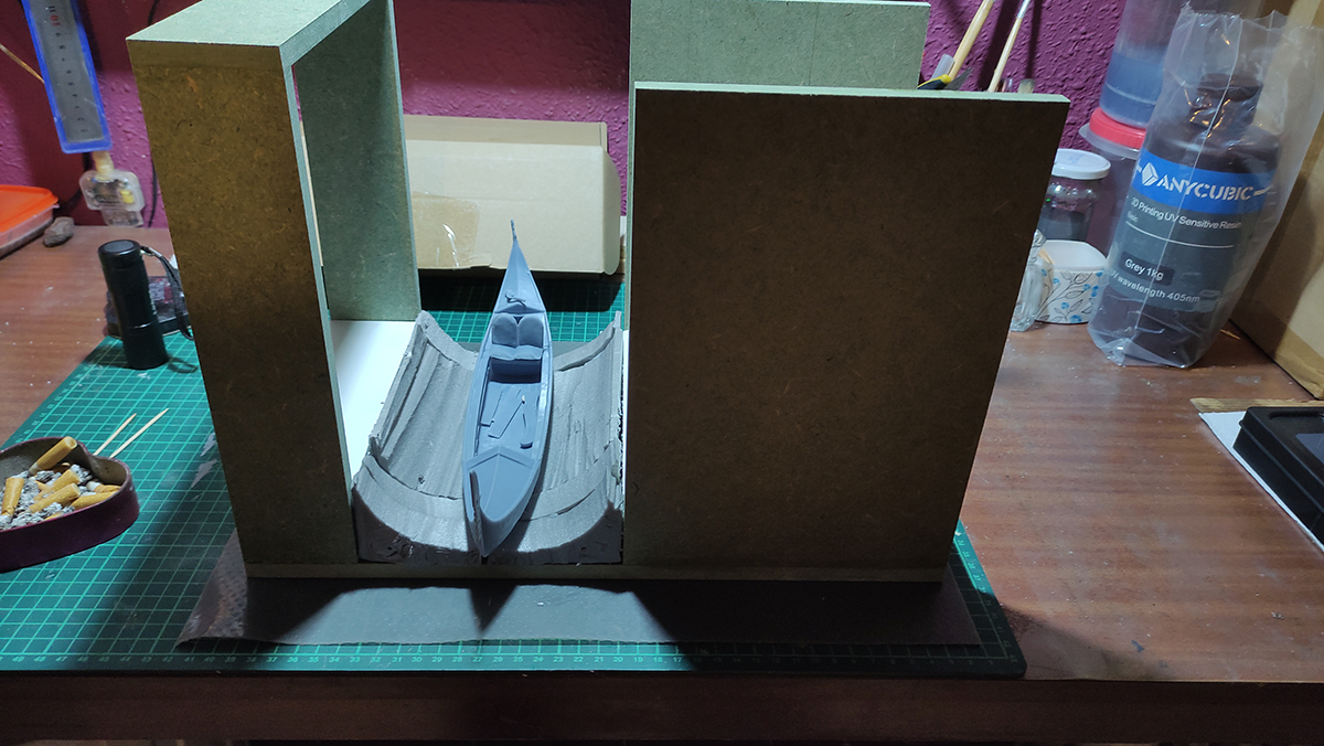 Diorama artesanal de Venecia durante la peste negra, mostrando a dos médicos de la peste con máscara frente a una góndola en un canal, con iluminación de farol.