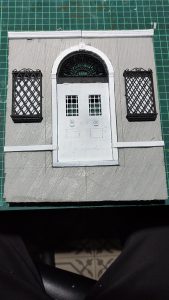 Diorama artesanal de Venecia durante la peste negra, mostrando a dos médicos de la peste con máscara frente a una góndola en un canal, con iluminación de farol.