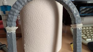 Diorama artesanal de Venecia durante la peste negra, mostrando a dos médicos de la peste con máscara frente a una góndola en un canal, con iluminación de farol.