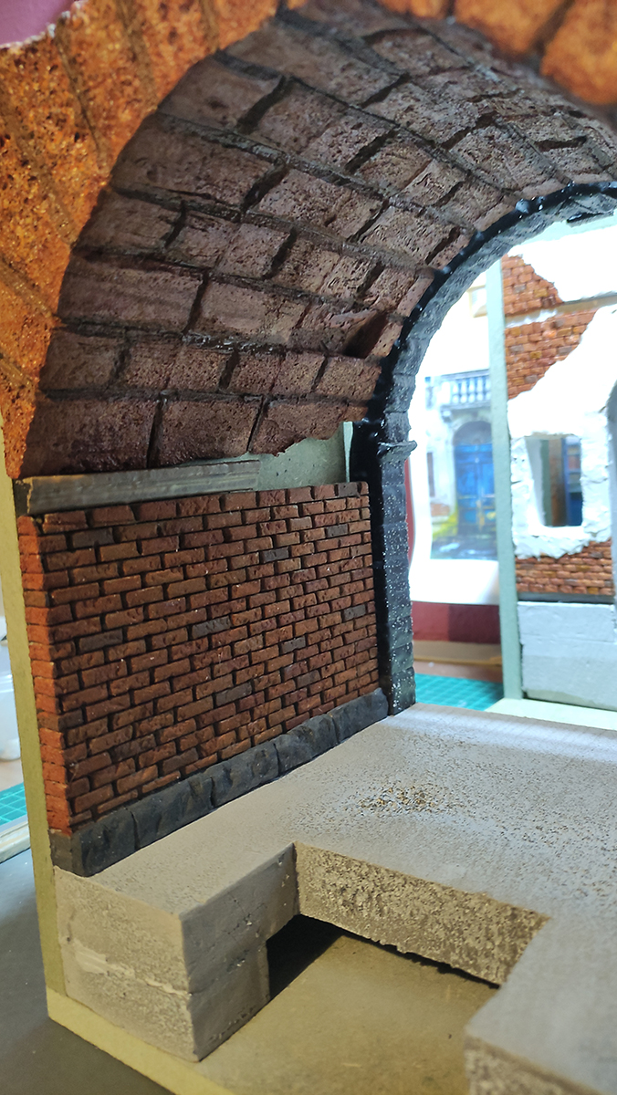 Diorama artesanal de Venecia durante la peste negra, mostrando a dos médicos de la peste con máscara frente a una góndola en un canal, con iluminación de farol.