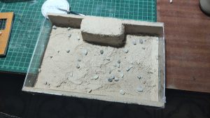 Diorama artesanal de Venecia durante la peste negra, mostrando a dos médicos de la peste con máscara frente a una góndola en un canal, con iluminación de farol.