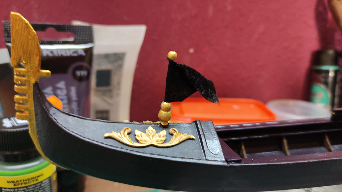 Diorama artesanal de Venecia durante la peste negra, mostrando a dos médicos de la peste con máscara frente a una góndola en un canal, con iluminación de farol.