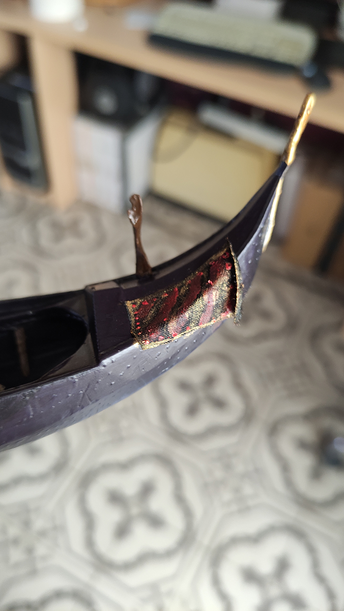 Diorama artesanal de Venecia durante la peste negra, mostrando a dos médicos de la peste con máscara frente a una góndola en un canal, con iluminación de farol.