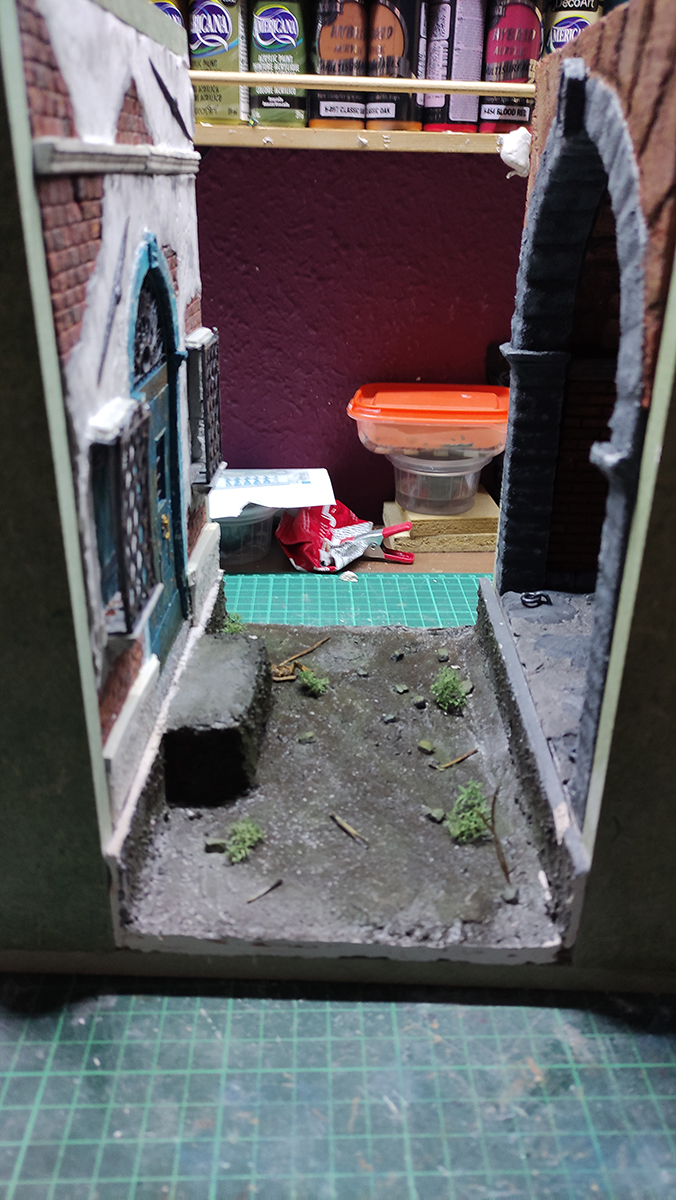 Diorama artesanal de Venecia durante la peste negra, mostrando a dos médicos de la peste con máscara frente a una góndola en un canal, con iluminación de farol.