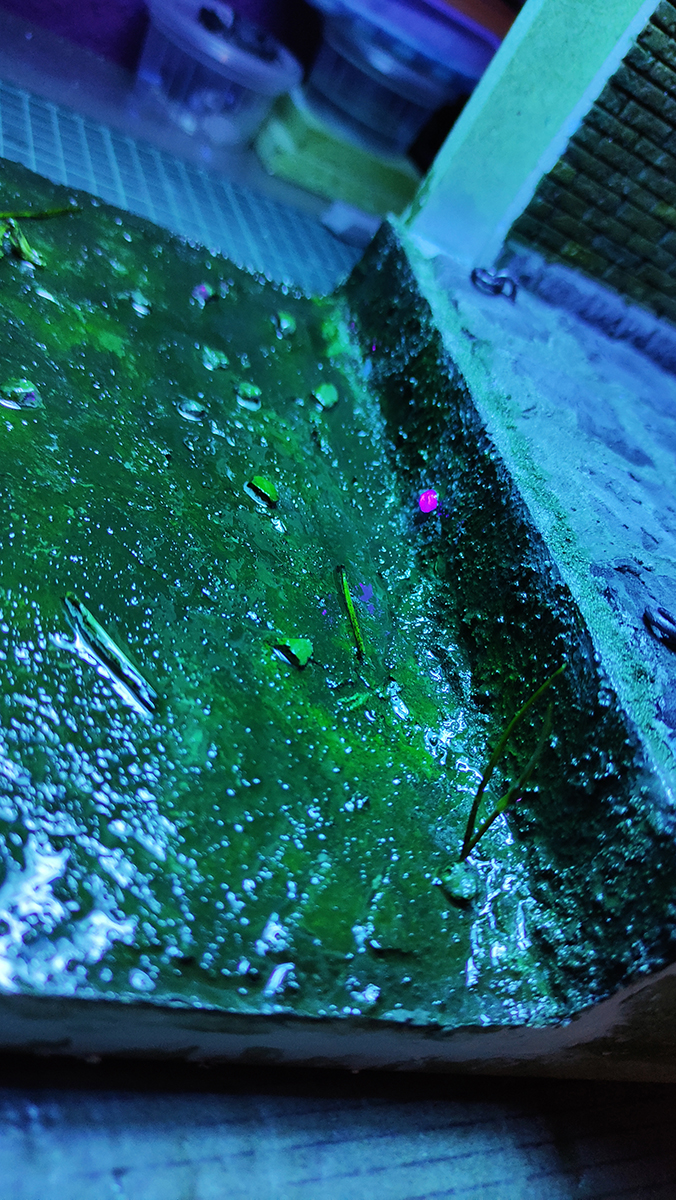 Diorama artesanal de Venecia durante la peste negra, mostrando a dos médicos de la peste con máscara frente a una góndola en un canal, con iluminación de farol.