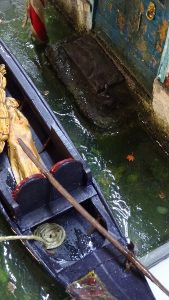 Diorama artesanal de Venecia durante la peste negra, mostrando a dos médicos de la peste con máscara frente a una góndola en un canal, con iluminación de farol.