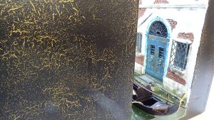 Diorama artesanal de Venecia durante la peste negra, mostrando a dos médicos de la peste con máscara frente a una góndola en un canal, con iluminación de farol.