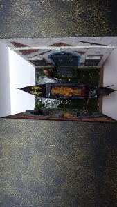 Vista superior del diorama de Venecia con góndola y cuerpos envueltos en mortajas, mostrando el acabado exterior artístico y la estructura del book nook.