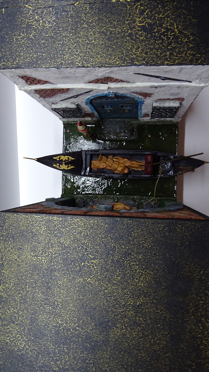 Vista superior del diorama de Venecia con góndola y cuerpos envueltos en mortajas, mostrando el acabado exterior artístico y la estructura del book nook.