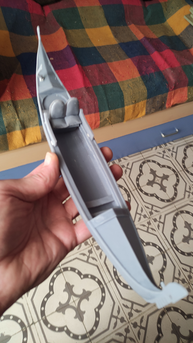 Diorama artesanal de Venecia durante la peste negra, mostrando a dos médicos de la peste con máscara frente a una góndola en un canal, con iluminación de farol.