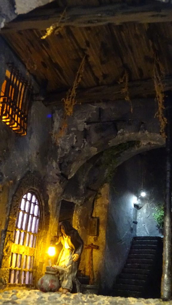 Miniatura artesanal del Hombre del Saco inspirada en la crónica negra española. Diorama con iluminación LED ambiente, texturas de piedra envejecida y detalles de realismo extremo por 27dioramas.