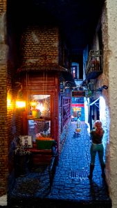 Diorama de una calle de París con fachadas de ladrillo, iluminación LED cálida y perspectiva forzada.