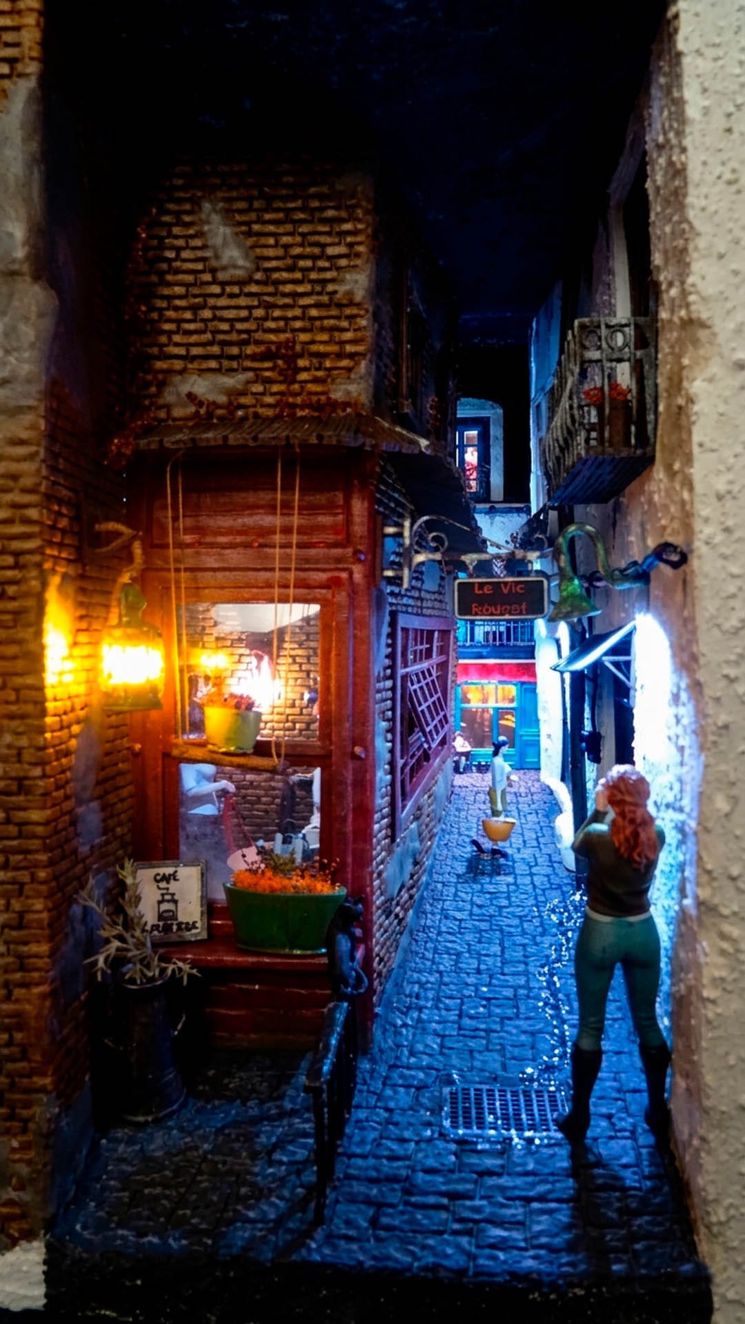 Diorama de una calle de París con fachadas de ladrillo, iluminación LED cálida y perspectiva forzada.