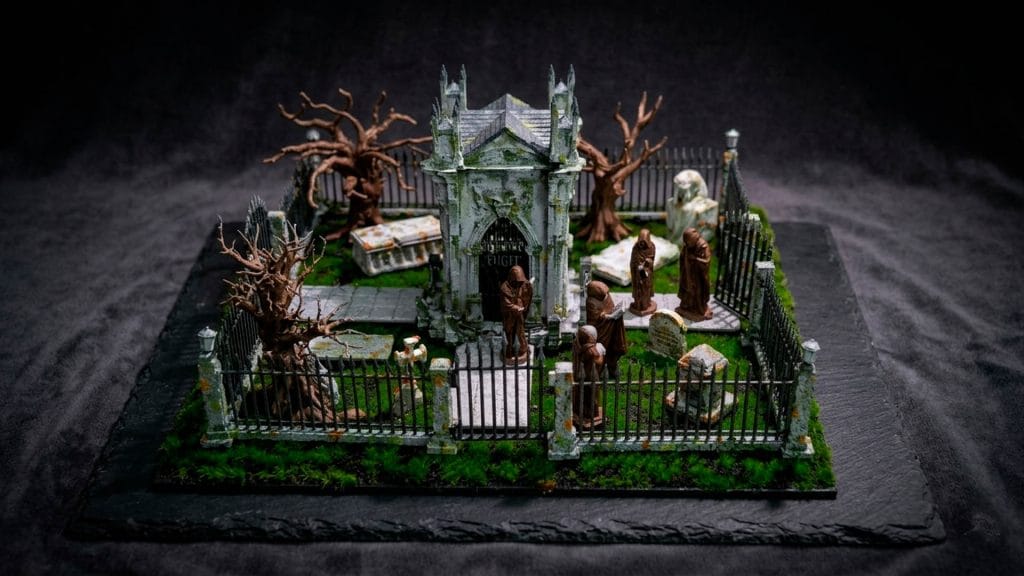 Diorama de un cementerio gótico artesanal con mausoleo central, monjes encapuchados y detalles de vegetación realista.