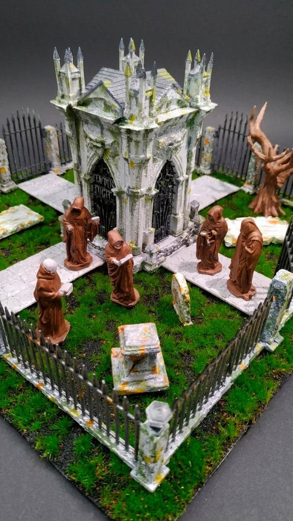Primer plano del diorama 'El Cementerio' mostrando a los monjes encapuchados rodeando el mausoleo central sobre musgo realista.