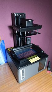 Detalle del equipo de impresión 3D de resina utilizado en el proceso de scratch building para fabricar accesorios y personajes detallados a escala.