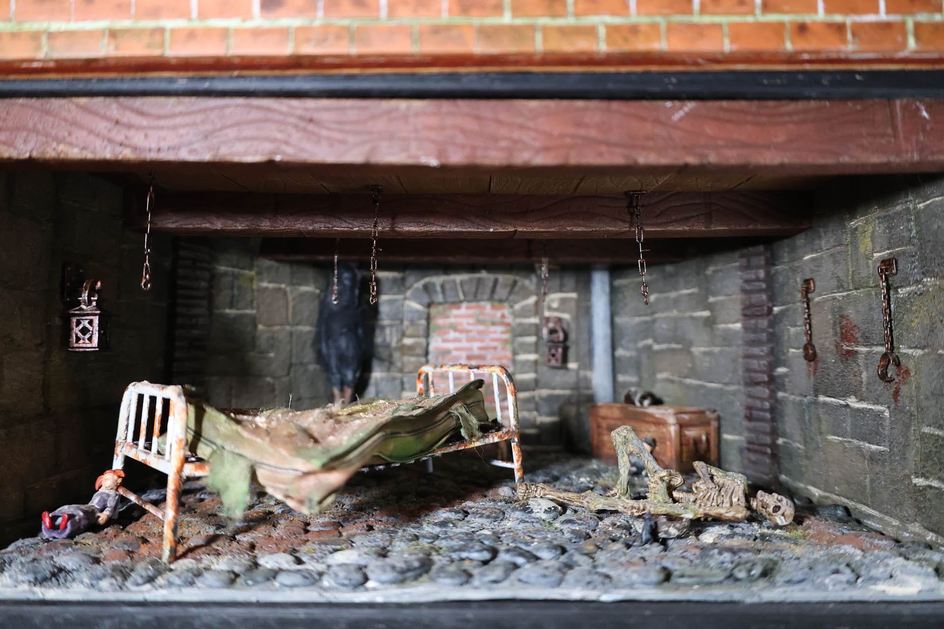 Diorama artesanal "La Casa" en miniatura: sección transversal de una vivienda estructurada por plantas, con diferentes escenas y sucesos narrativos en cada nivel, detalles de interiores hiperrealistas e iluminación ambiental