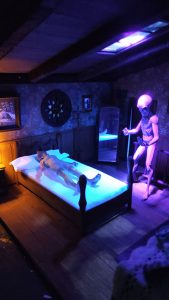 Diorama artesanal 'La Casa' de 27 Dioramas, una estructura de varias plantas construida con madera, papel y ladrillos de barro, con figuras de resina UV en escenas interiores detalladas.