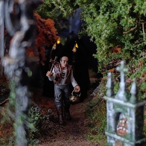 Diorama artesanal de leyenda gallega con figura de aldeano portando cruz y caldero en un camino oscuro con cruceiro, inspirado en el folclore ibérico