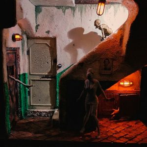 Diorama artesanal inspirado en Silent Hill con escena de pasillo siniestro, criatura y figura femenina iluminadas con luz naranja, pieza única de coleccionismo